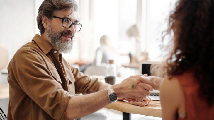 Business professionals shaking hands during a meeting at a desk